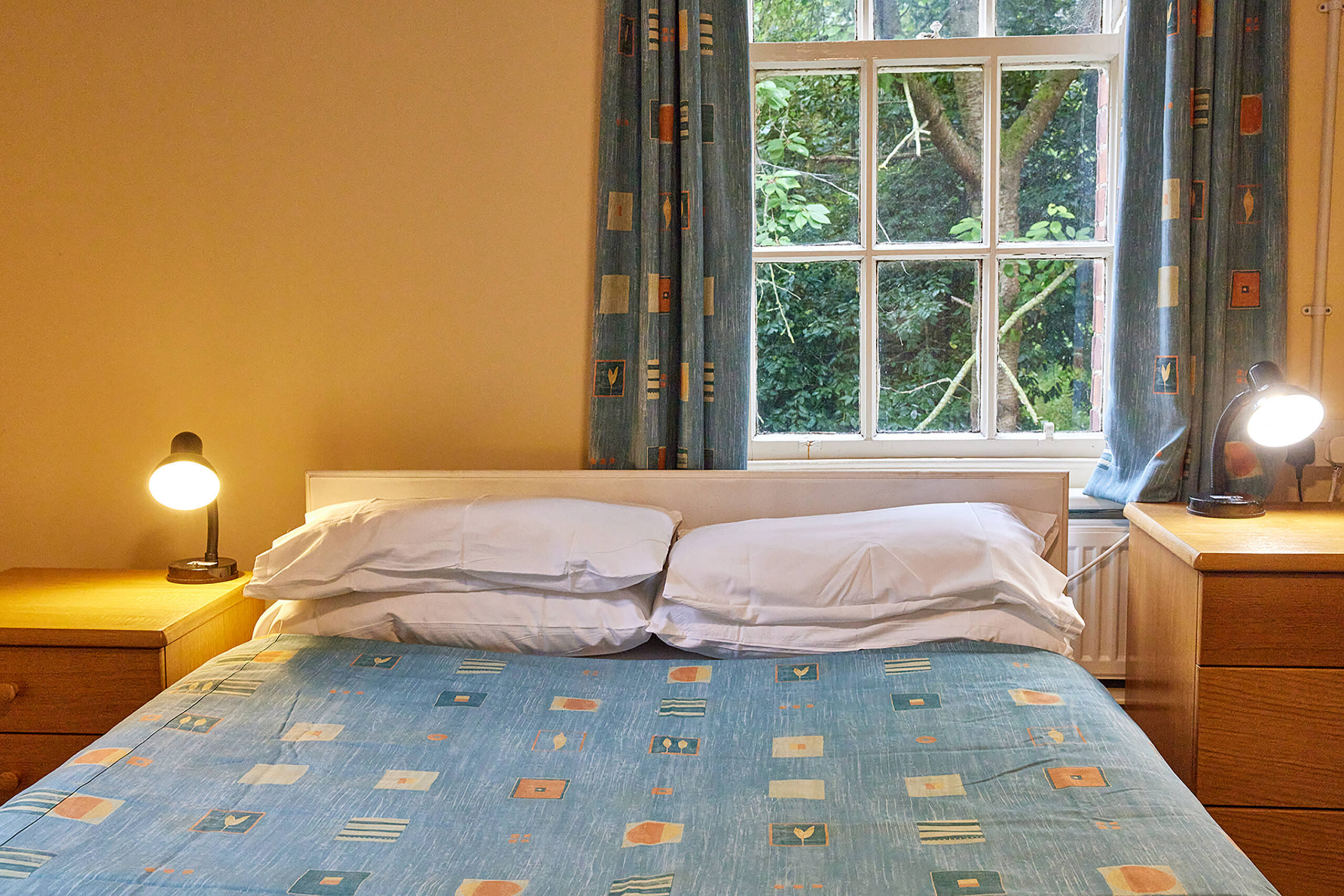 a bed with blue sheets below a window