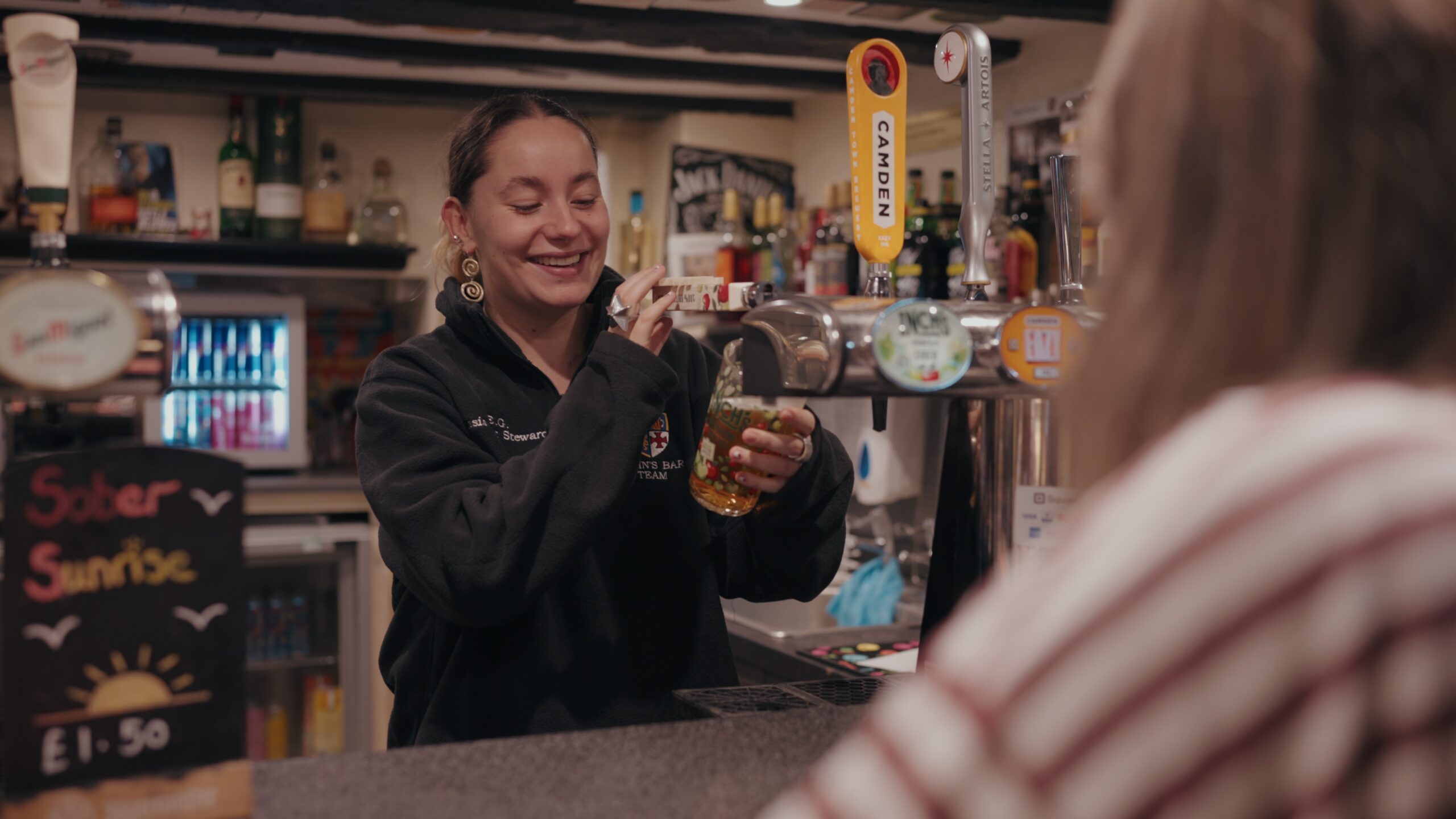 A young woman pulls a pint