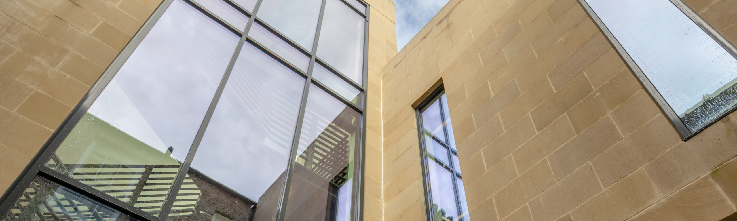 large reflective windows in a creamy stone wall