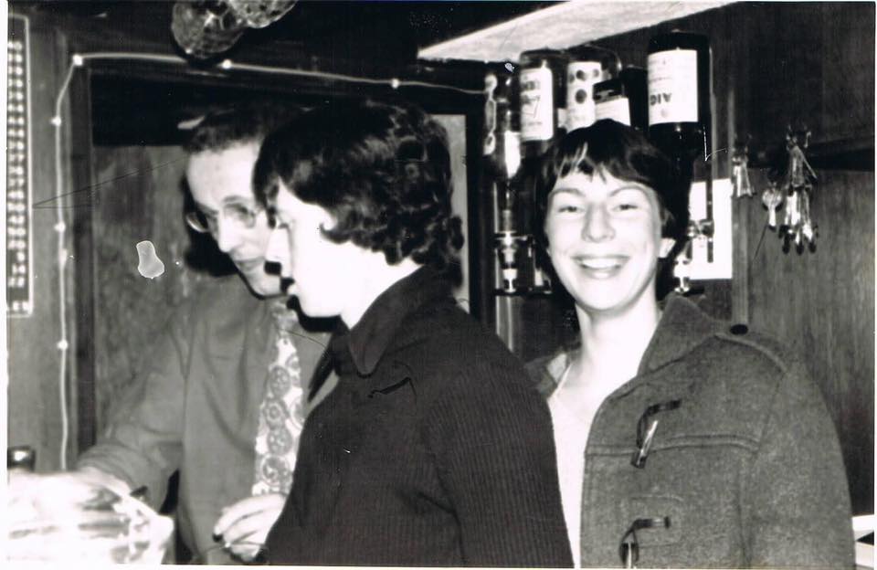 a group of three young people stand behind the bar