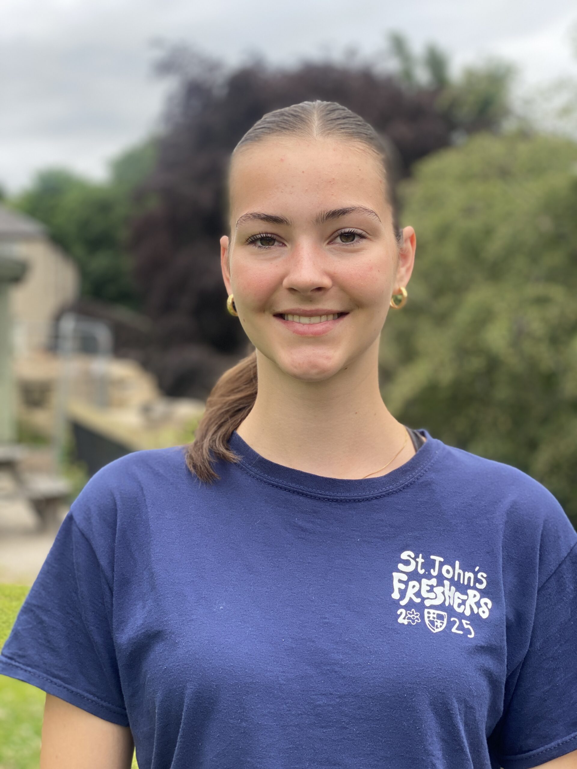 A young woman in a blue t shirt smiles at the camera